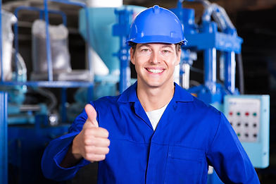 Skilled industrial worker wearing safety gear giving a thumbs-up inside a professional facility.