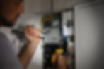 Electrician inspecting and repairing a residential electrical breaker panel indoors