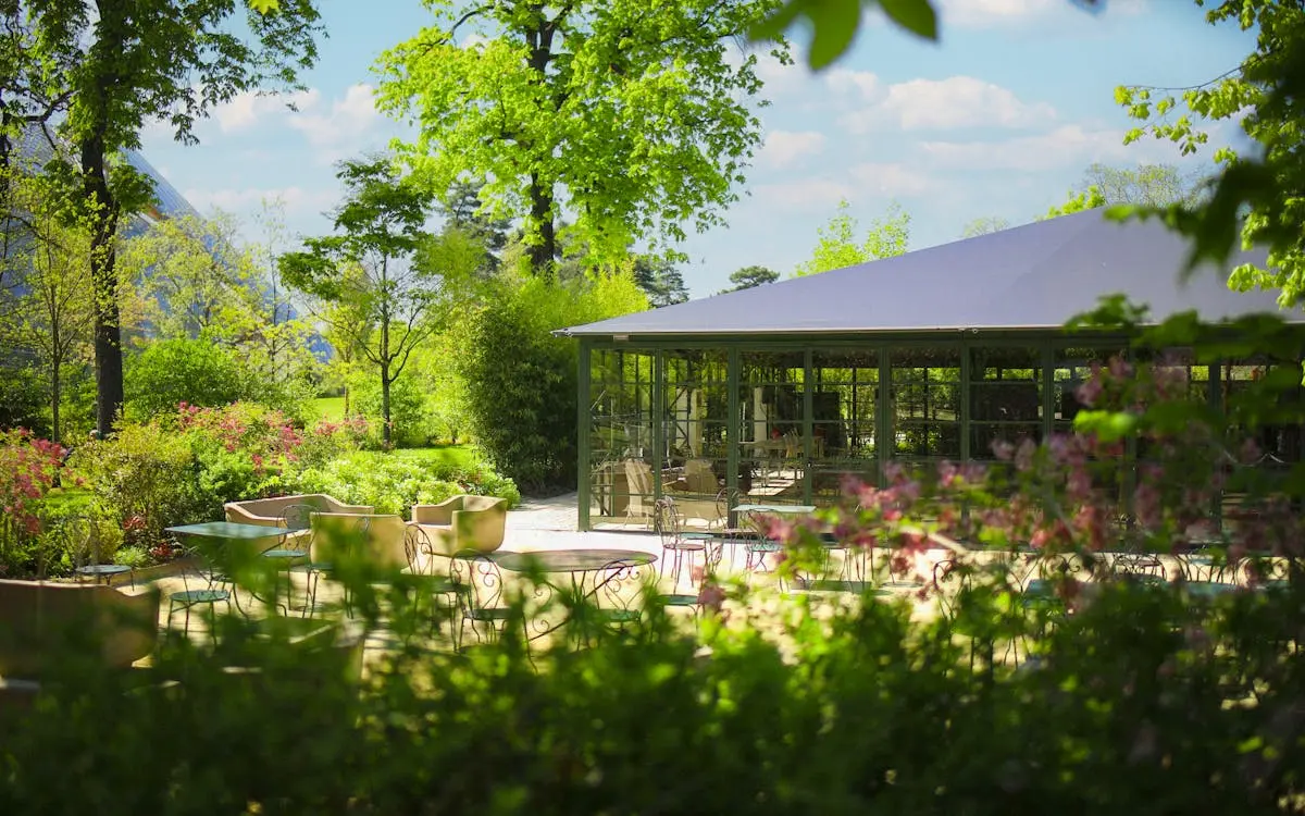 Orangerie avec terrasse en pleine nature au milieu du jardin d'acclimatation au bois de boulogne, orangerie avec grande verrière de l'extérieur