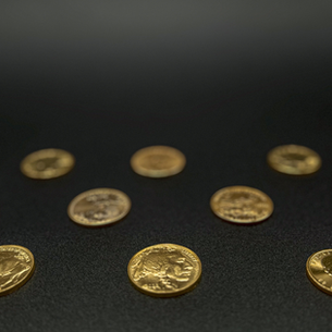 Gold buying and gold coins arranged on a dark display surface