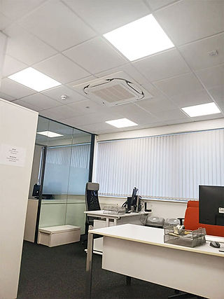 open-plan office featuring a discreet ceiling cassette air conditioning unit installed in a suspended tile ceiling, providing even airflow for employees