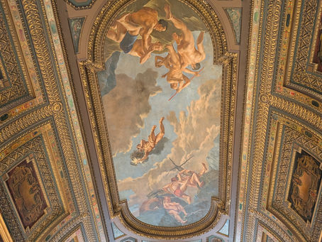 Painted mural ceiling inside the New York Public Library with ornate architectural details and soft lighting