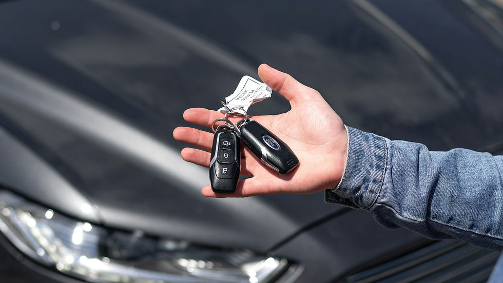 Hand hält Autoschlüssel mit Ford-Logo vor einem dunklen Mietwagen – Symbolbild für Mietwagenbuchung bei Sixt mit Studentenrabatt.