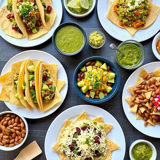 table with spread of tacos burittos nachos salsa verde salsa guacamole beans, pico cheese.