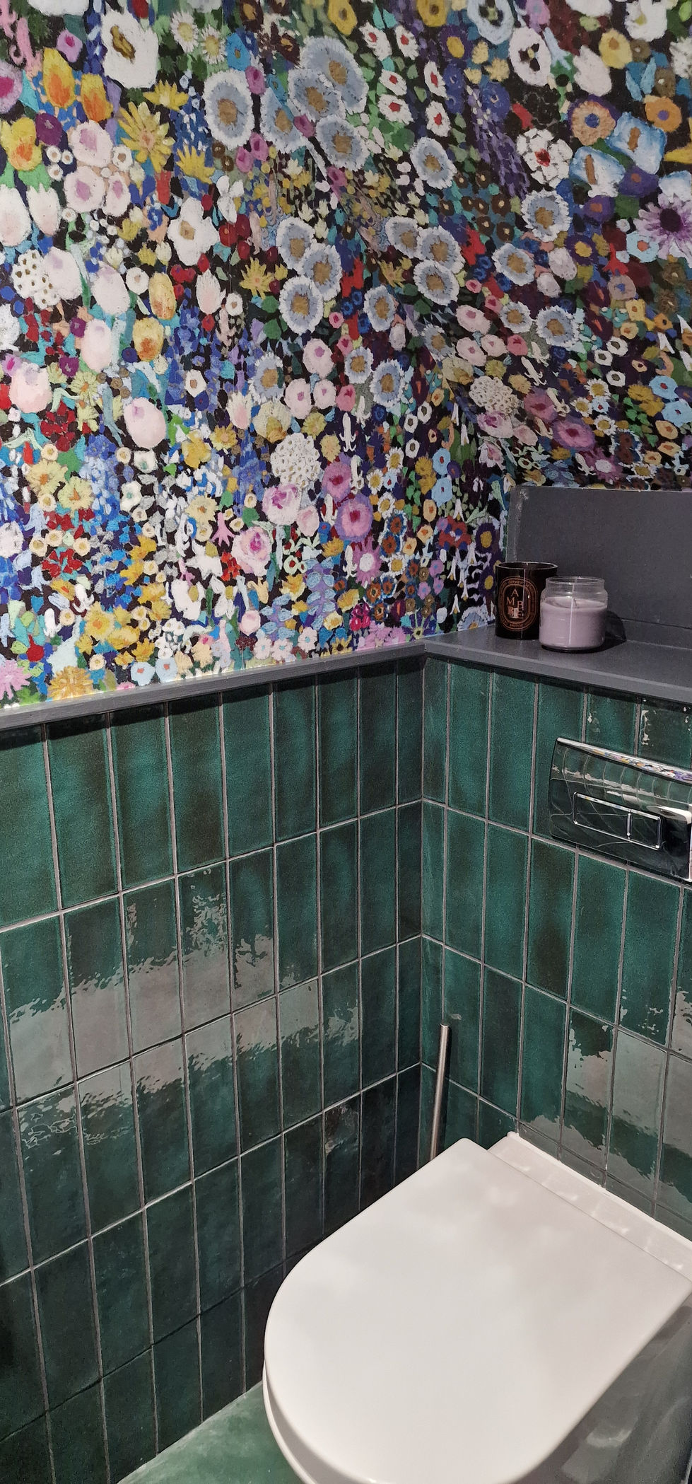 a bathroom with green tiles and a diptyque candle