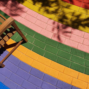 a wooden chair sits on a rainbow colored brick walkway