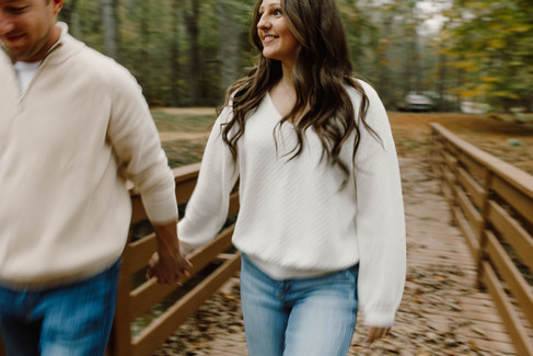 A blurred fall photograph of a couple walking hand in hand on a bridge