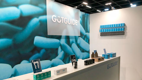 GutGuide®-messuosasto, jossa näkyy takaseinällä mikroskooppikuva maitohappobakteereista, tiski ja tiskillä bakteerilisien pakkauksia