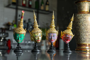 A row of thai crown doll heads on top of bar counter.