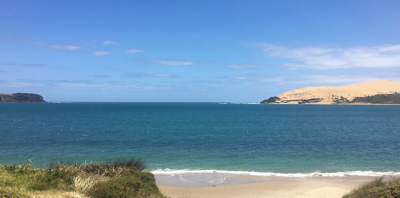 A photo of the Hokianga harbour looking our to Arai Te Uru and the sand dunes from the beach at Omapere
