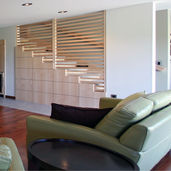 The presence of a wood stairway wall in a contemporary home effortlessly infuses the modern interior design with a natural and inclusive warmth. By blending wood with sleek lines, an alluring and welcoming ambiance is created. The utilization of wood also fosters a feeling of harmony with nature, resonating a sense of tranquility and rootedness within the space. Whether it's a lighter or darker wood tone, the stairway wall can confidently stand out as a focal point, enriching the overall aesthetic appeal of the home.