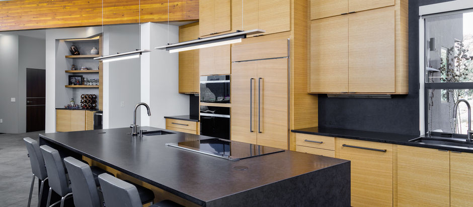 Modern Sedona custom kitchen featuring an engineered quartz waterfall island with integrated induction cooktop, warm wood cabinetry, and sweeping red rock views.