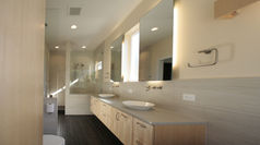The bathroom design features back lighted mirrors, floating cabinets, and blond wood for a modern and sleek look. The concrete countertops add an industrial touch, while the open shower creates a spacious and airy feel. The combination of these elements creates a contemporary and minimalist aesthetic, perfect for a clean and organized bathroom space. The back lighted mirrors provide a soft and flattering lighting for getting ready, while the floating cabinets offer storage without taking up floor space. The use of blond wood adds warmth and a natural element to the overall design. With the open shower, the bathroom feels more expansive and allows for easy access and movement. This design concept combines functionality with style, creating a harmonious and inviting bathroom environment.