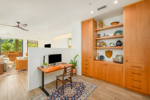 Interior view of a den and home office in a Southwest Contemporary Sedona remodel, featuring a desk and expansive custom wood cabinetry designed for storage and memorabilia display.