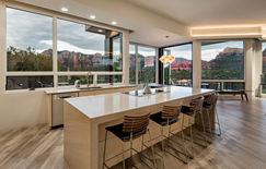 The modern kitchen island in Sedona, Arizona features a striking view and a sleek engineered quartz waterfall edge. It is equipped with an efficient induction cooktop, combining style and practicality.