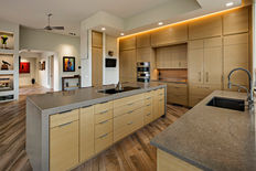 The important features of the chef side of a kitchen island for cooking and entertaining include a spacious and durable countertop for food preparation, a built-in cooktop or stove for easy access to cooking appliances, ample storage for pots, pans, and utensils, and a sink close by for convenient cleanup. Additionally, having seating options such as bar stools or chairs allows for guests to interact with the chef while they cook and creates a social atmosphere for entertaining. Lighting fixtures above the chef side of the island are also crucial for visibility while cooking and creating a welcoming ambiance for guests. Finally, incorporating a wine cooler or beverage fridge can enhance the entertaining experience by providing easy access to drinks for guests.