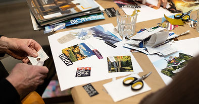 table with various papercraft supplies. Participants are seated around the table, actively engaging in vision board making.