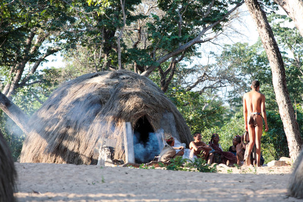 San people by a grass hut, Namibia photography by Will Gray