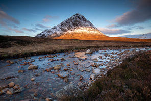 Buachaille Etive Mòr mountain lit by golden sunrise over a stream