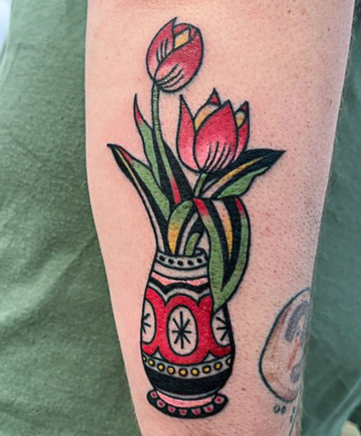 Two bright tulips, one seriously fun vase. This colorful floral tattoo pairs bold blooms with an ornate patterned vase for a piece that feels equal parts classic and playful. A little vintage, a little weird, and definitely not your grandma's flower arrangement.