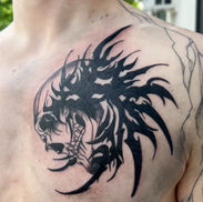 Black tribal-style skull tattoo on the chest by Sam at Acme Tattoo Co.