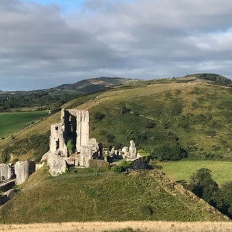 Corfe Castle with high ridge of Purbeck Hills in distance