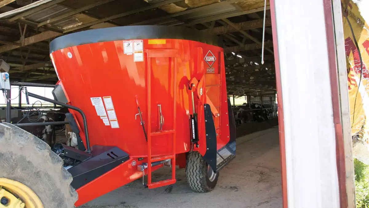 KUHN VS 100 Series Single-Auger TMR Mixer attached to tractor rear, in barn