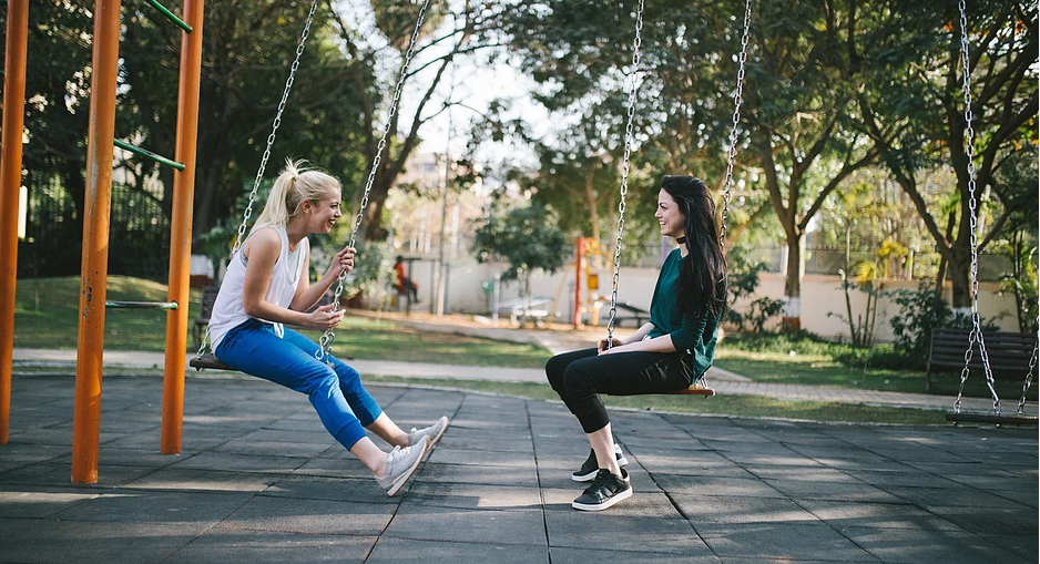 two_friends_smiling_on_swing_set
