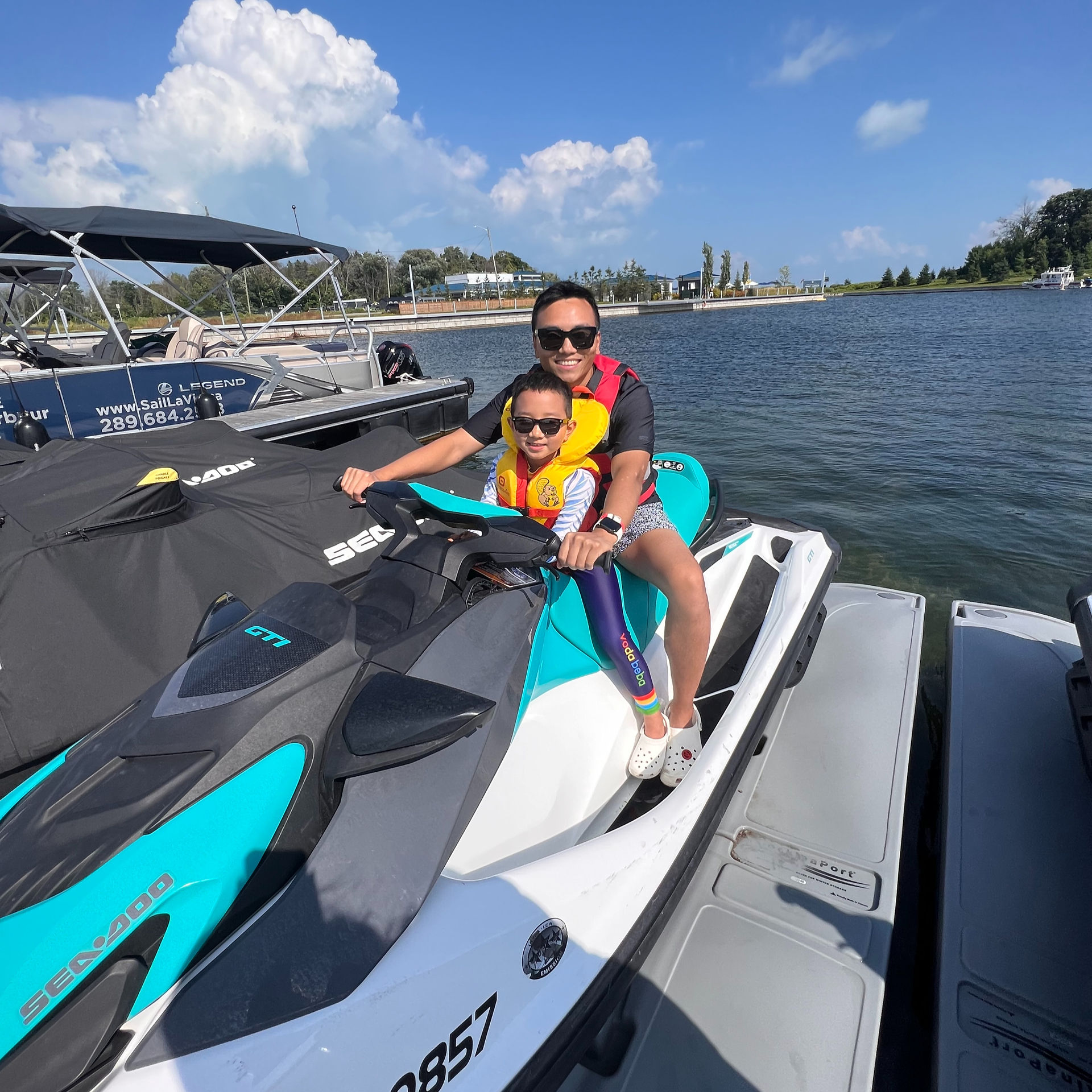 Man and child smiling on jetski sunny day