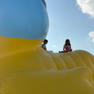 Two kids sitting on top of giant inflatable duck back