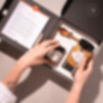 Foto do Kit Afável aberto, mostrando o manifesto, a colher personalizada e os méis.