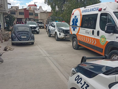 Unidades de emergencia y patrullas con torretas encendidas resguardando una calle perimetral de la comunidad de Zapotlán.