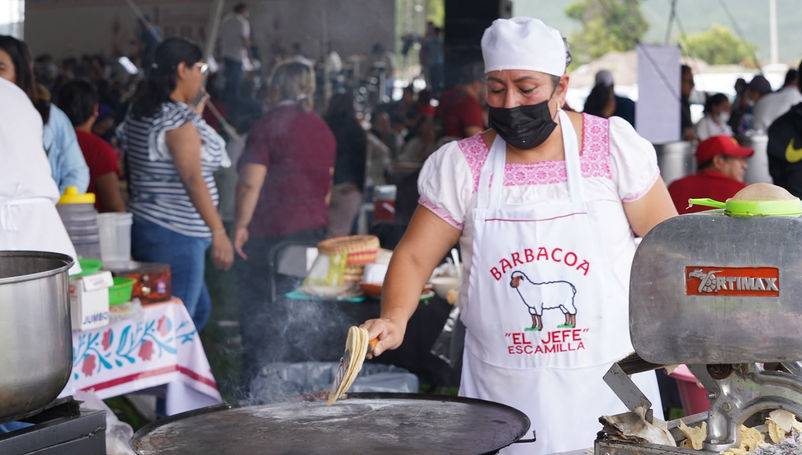 Expositores sirviendo consomé y platillos tradicionales durante el Festival de la Barbacoa del Valle del Mezquital en Hidalgo.