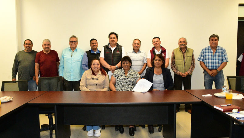 Vecinos de la comunidad de Jaltepec y autoridades de Tulancingo firmando un documento de acuerdos sobre una mesa.