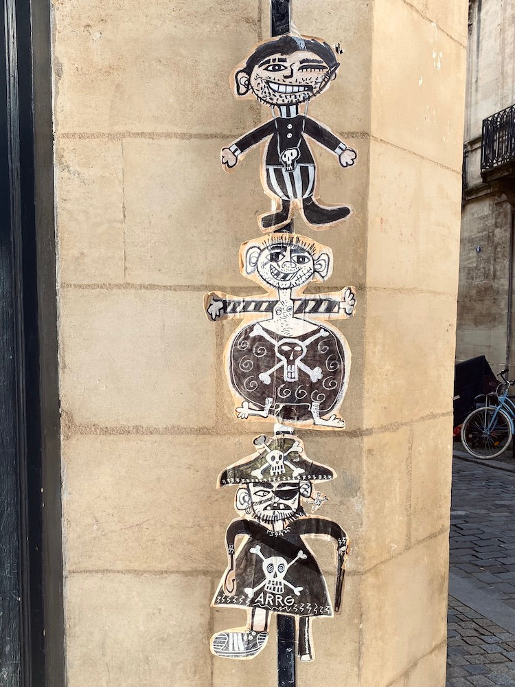 black and white pirates painted on cut out cardboard stuck to a street sign.