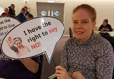 a female member holding up a large speech bubble prop which says "i have the right to say no"
