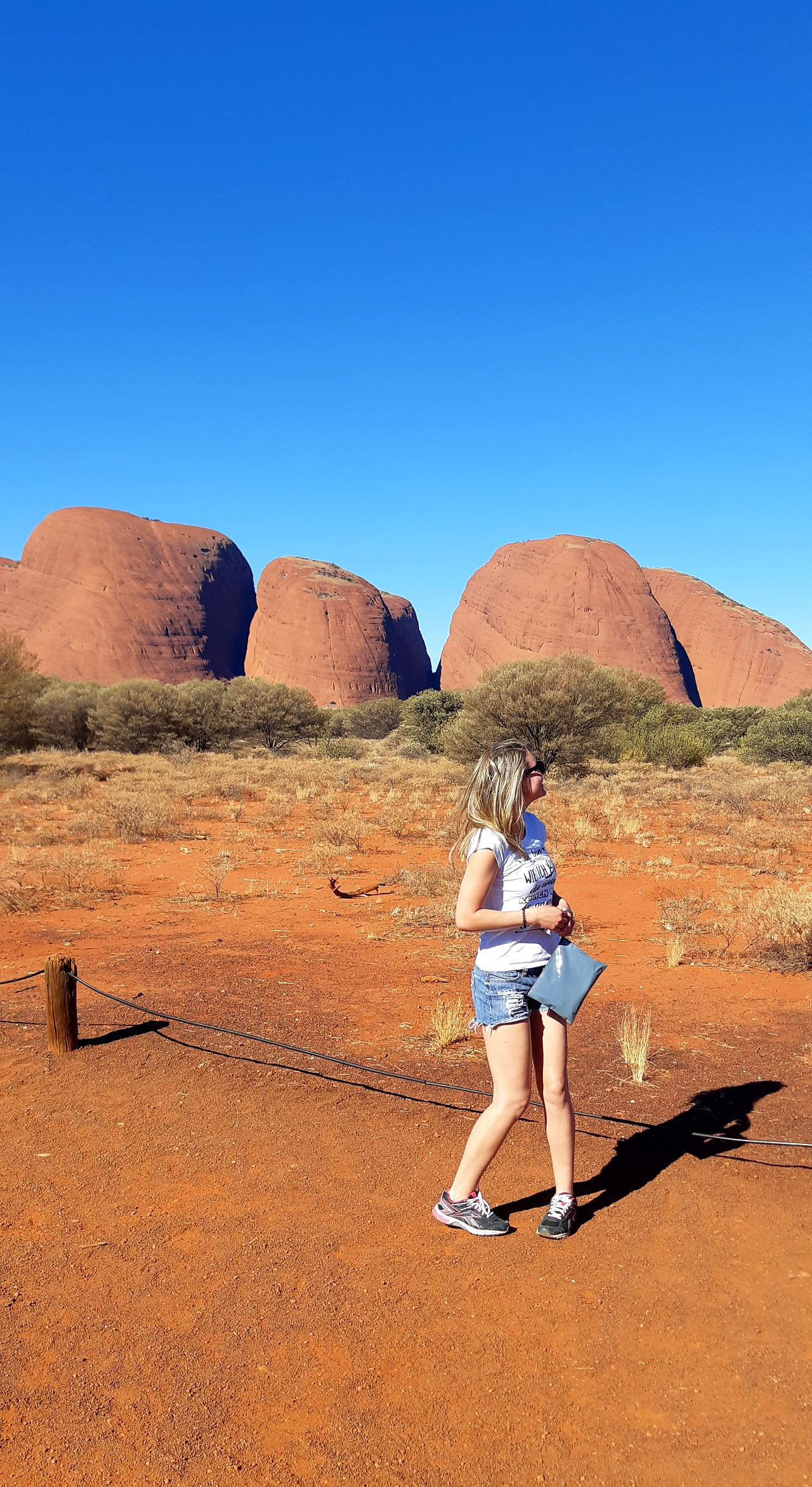 Frau steht vor den berühmten Olgas im australischen Outback bei traumhaften Wetter und blitzblauen Himmel
