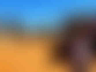 Mann im Camping-Areal im australischen Outback mit Tipi-Zelter im Hintergrund und goldener Sandboden