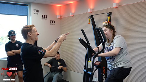 Trainer encouraging woman on a ski machine in a gym setting.
