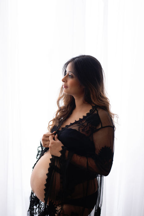Pregnant woman in a black dress posing in a professional studio maternity photoshoot in wargrave Berkshire.