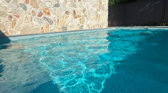 A luxury concrete pool next to a stone wall