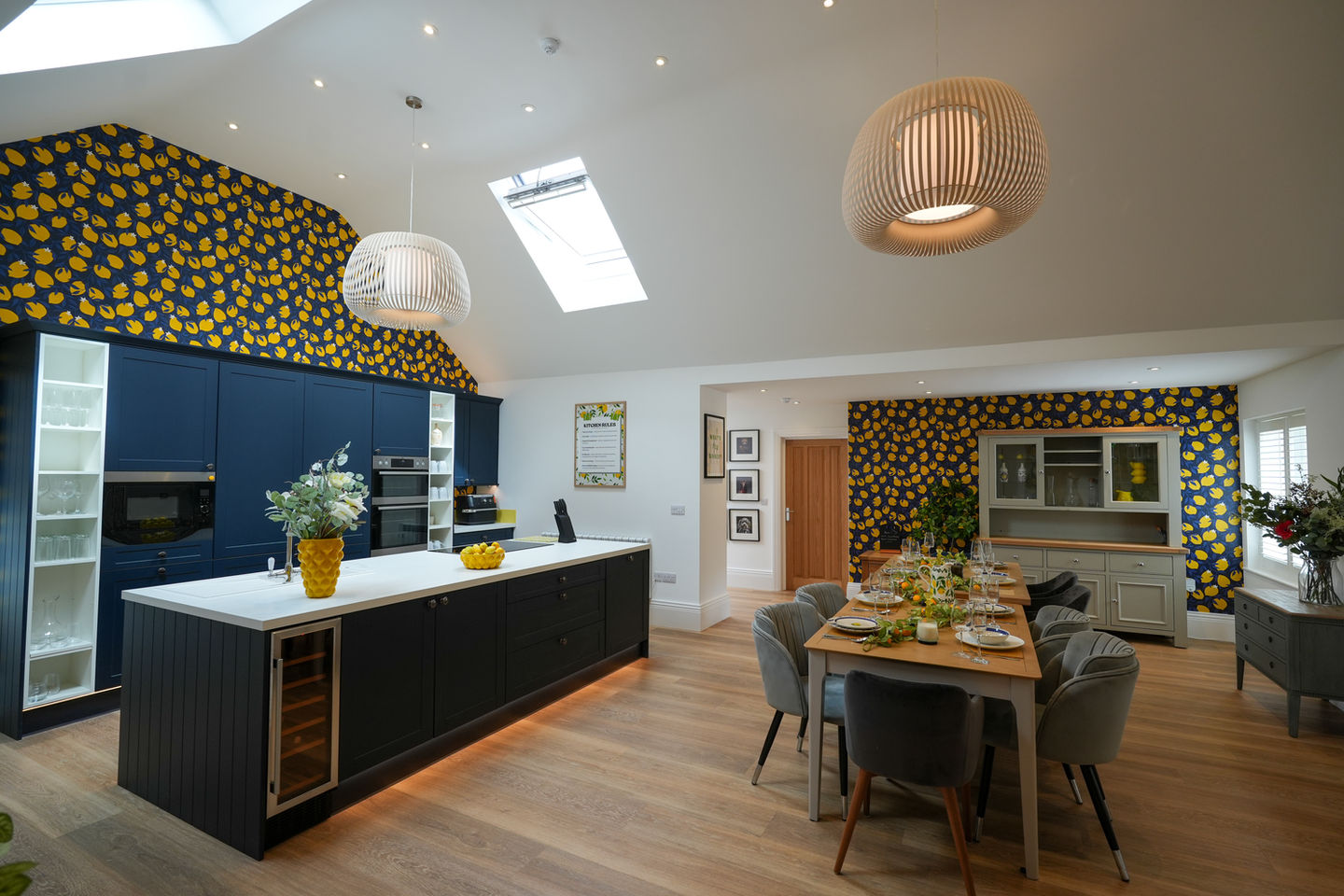 Modern open-plan kitchen and dining room with lemon wallpaper at Lemon Squeezy House in Rutland.