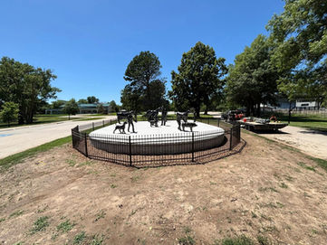 Round ornamental metal fence encircling bronze cowboy and horse sculptures