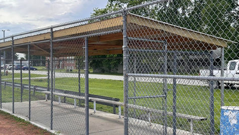 Fence contractors installing galvanized chain link fence at sports facility