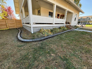 Curved decorative concrete curbing around porch foundation plantings