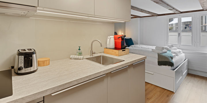 Combined kitchen and living area with coffee machine and dining counter in Ariser - Zug Unique Apartment in Historic Building.

