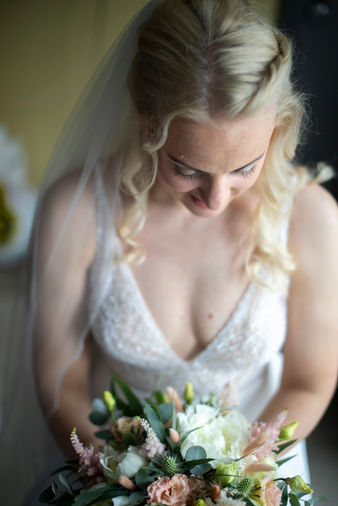 Portrett av brud som ser ned på blomstene hun holder i før bryllupet.