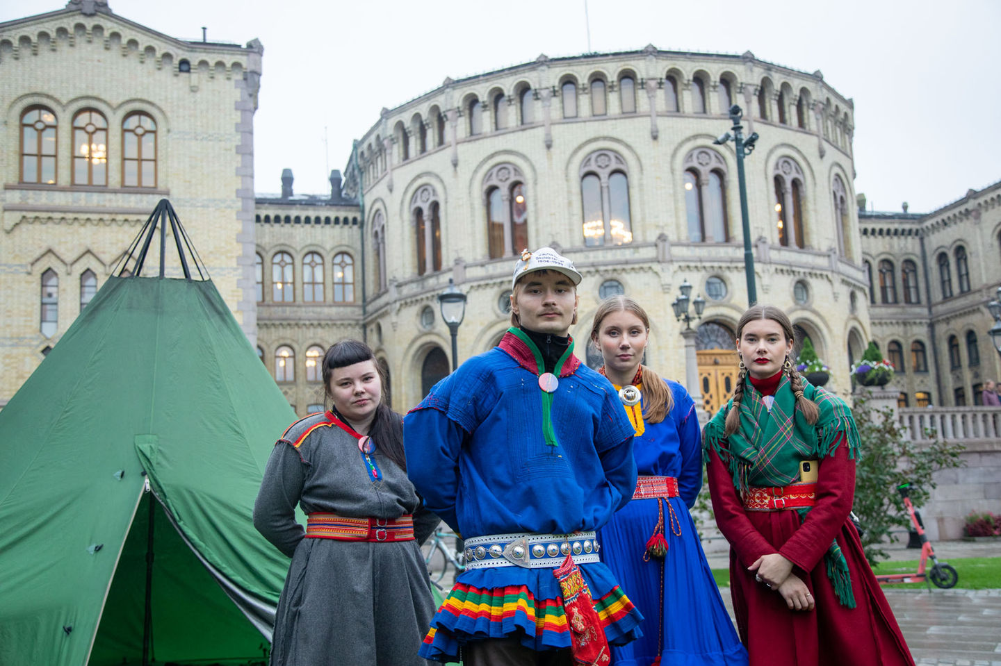 En gruppe samiske unge mennesker ser alvorlig i kamera under en demonstrasjon utenfor Stortinget i Norge