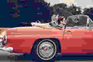 Couple Riding Red Ford Thunderbird during Daytime