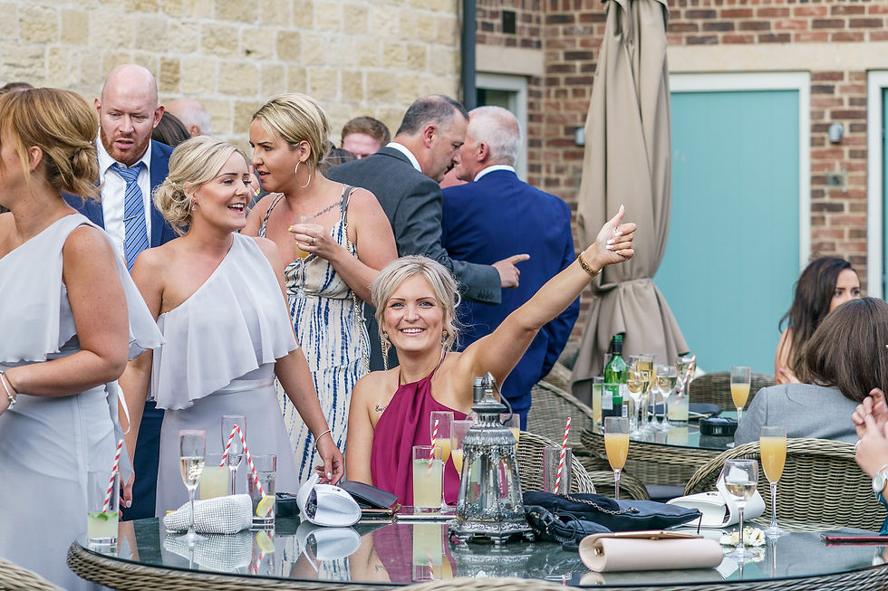 A group of wedding guests enjoy a wedding pre party of sax and DJ on the terrace outside Priory Cottages wedding venue, Wetherby